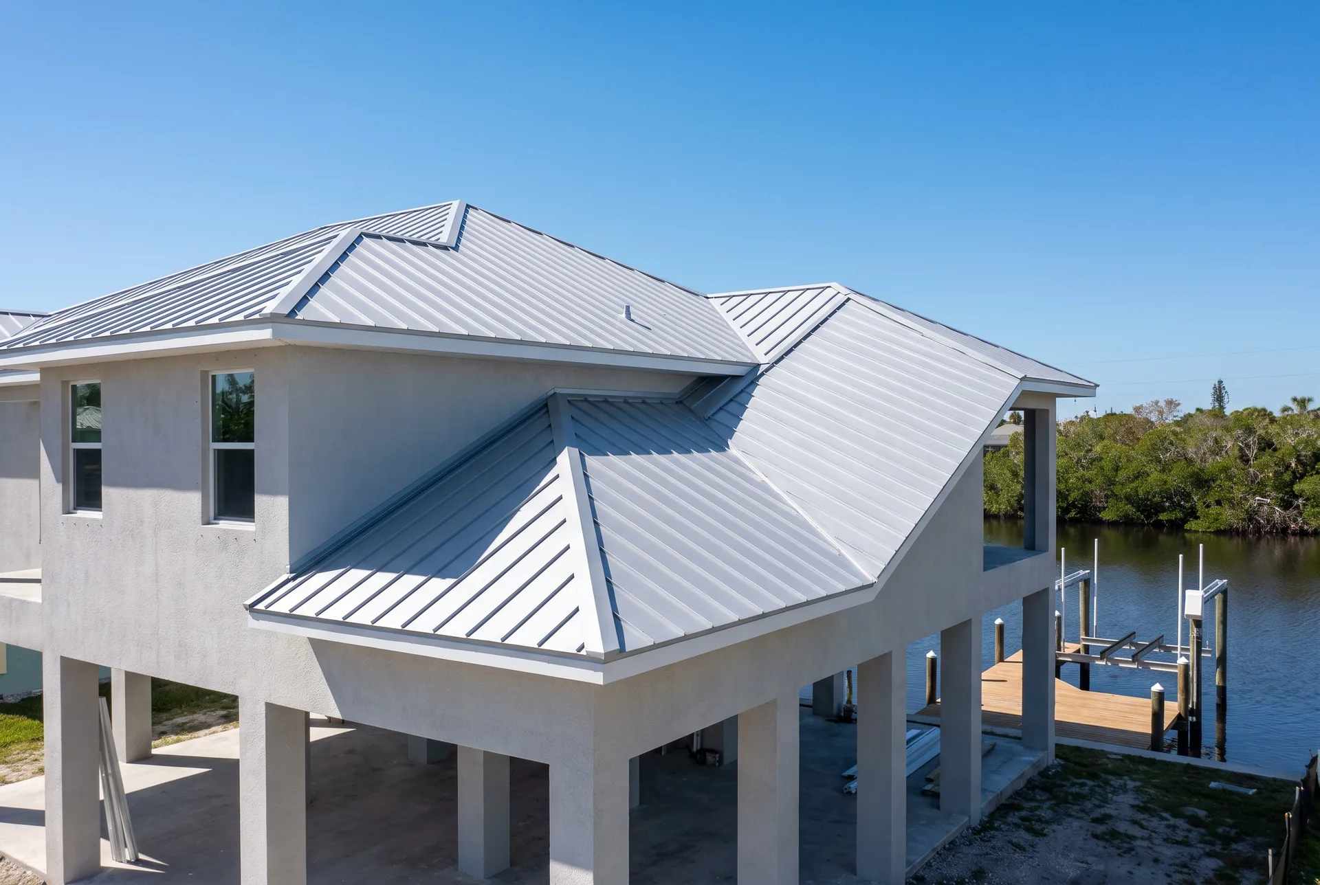 Standing-seam metal roof on an elevated Gulf-access home in Cape Coral with the canal behind it
